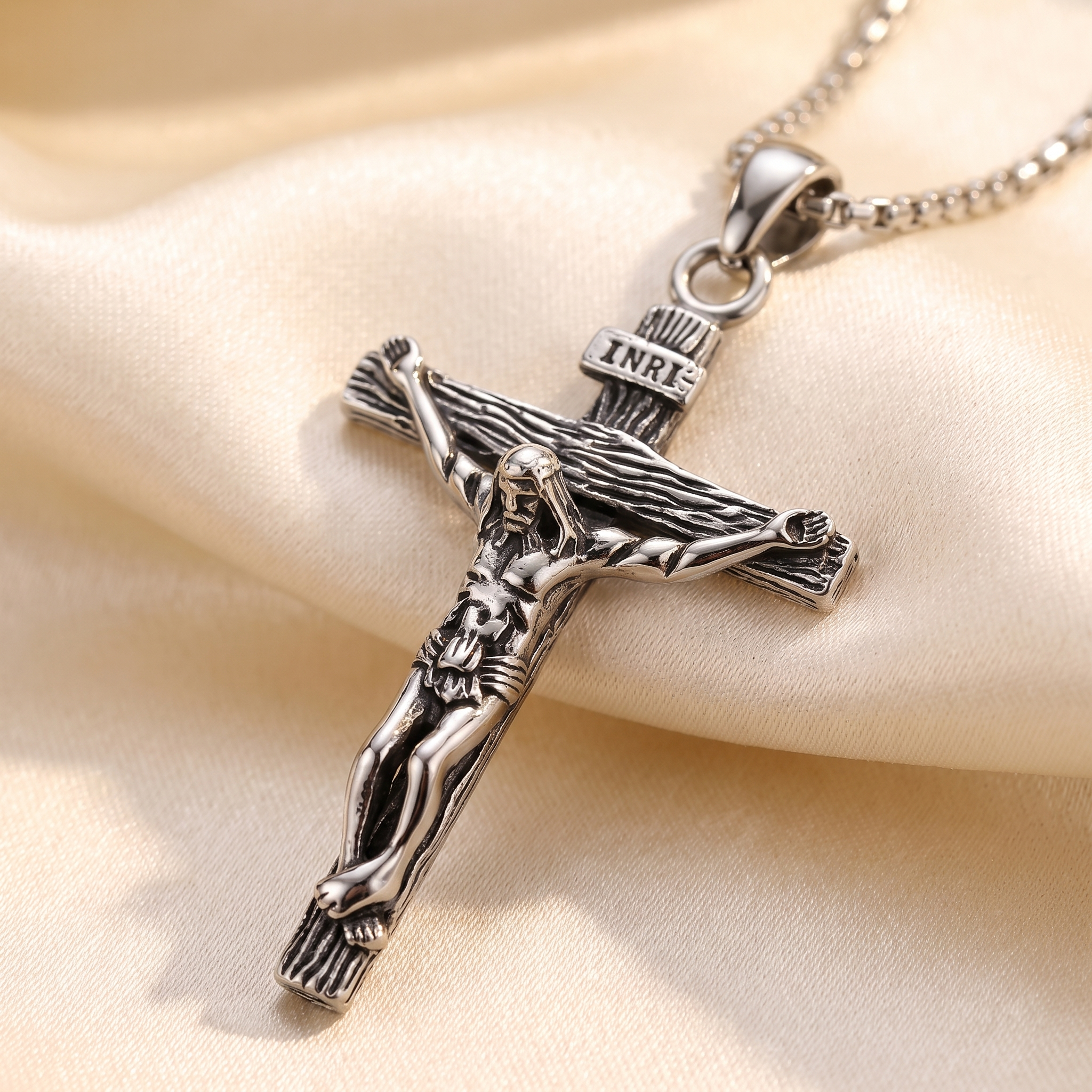 Colgante Crucifijo de Jesús con INRI en acero inoxidable 316L – detalle macro sobre satén