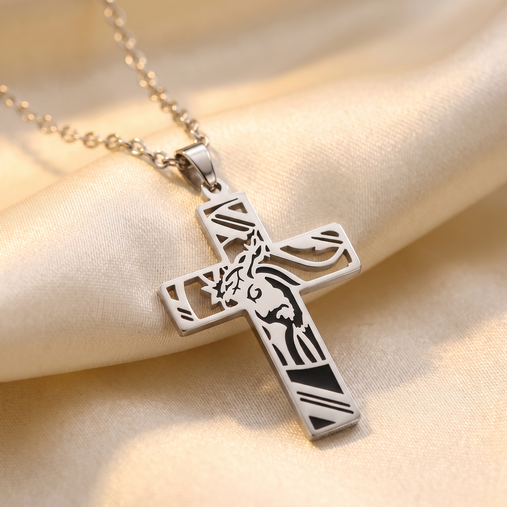Collar de Cruz de acero inoxidable con corona de espinas y silueta de Jesús – detalle macro sobre satén