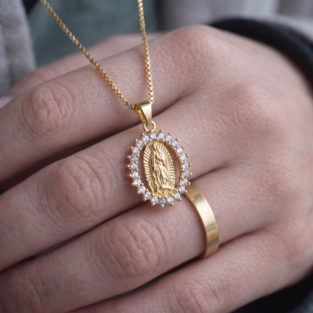 Collar Virgen de Guadalupe, medalla ovalada dorada con marco de circonias blancas – escala real en la mano