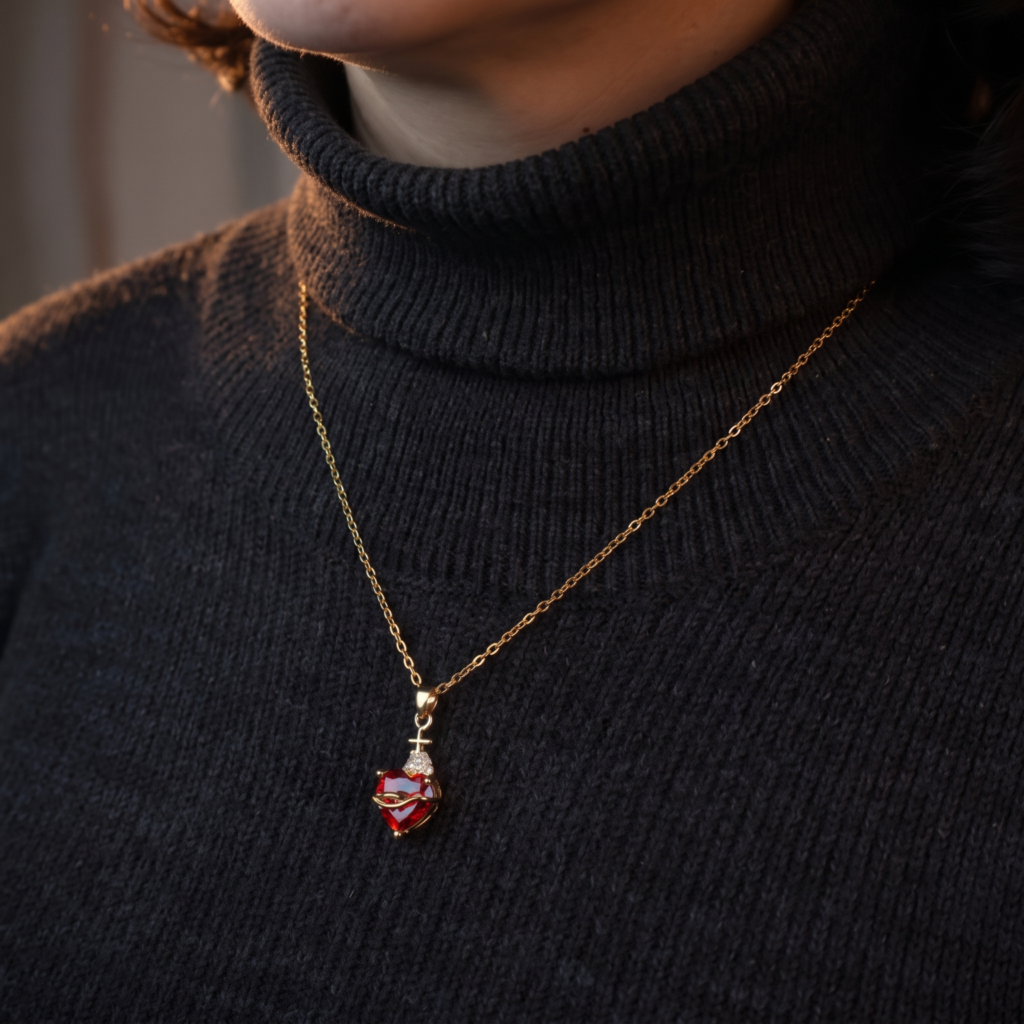 Collar del Sagrado Corazón de Jesús con cristal rojo en forma de corazón, cruz dorada y circonitas – sobre suéter oscuro, contraste elegante