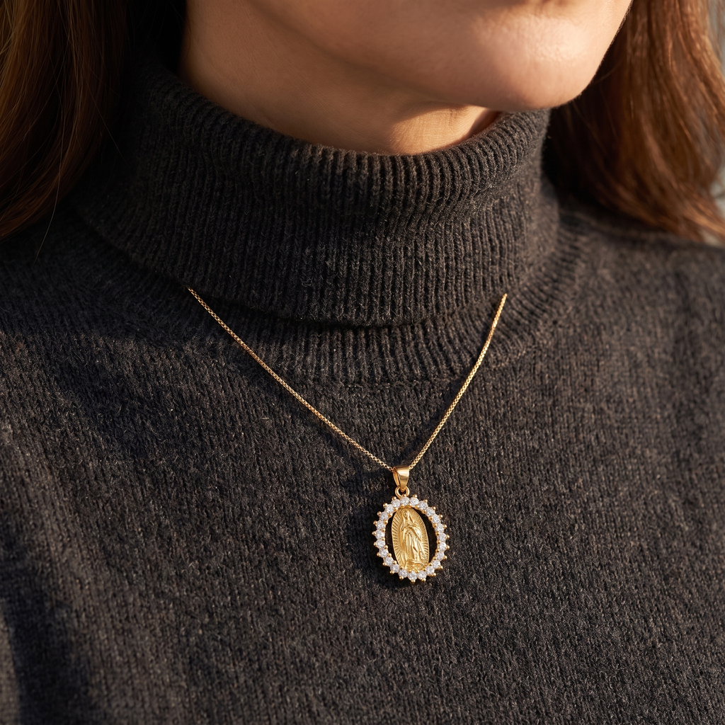 Collar Virgen de Guadalupe, medalla ovalada dorada con marco de circonias blancas – sobre suéter oscuro