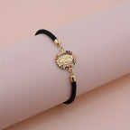Pulsera Virgen Maria - Cordon Ajustable Banado en Oro 24K sobre superficie de madera — presentacion del producto