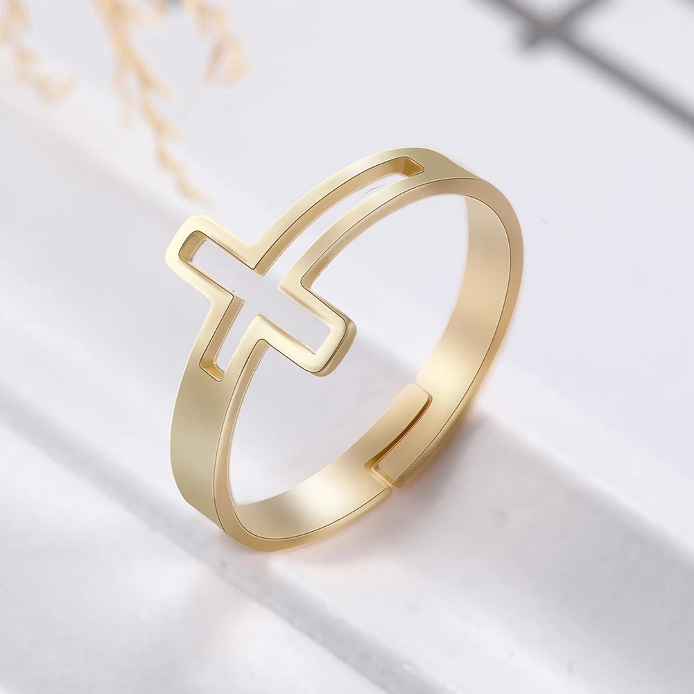 Anillo con cruz minimalista en dorado sobre fondo cálido