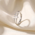 Anillo cruz con circonias plateado sobre seda marfil