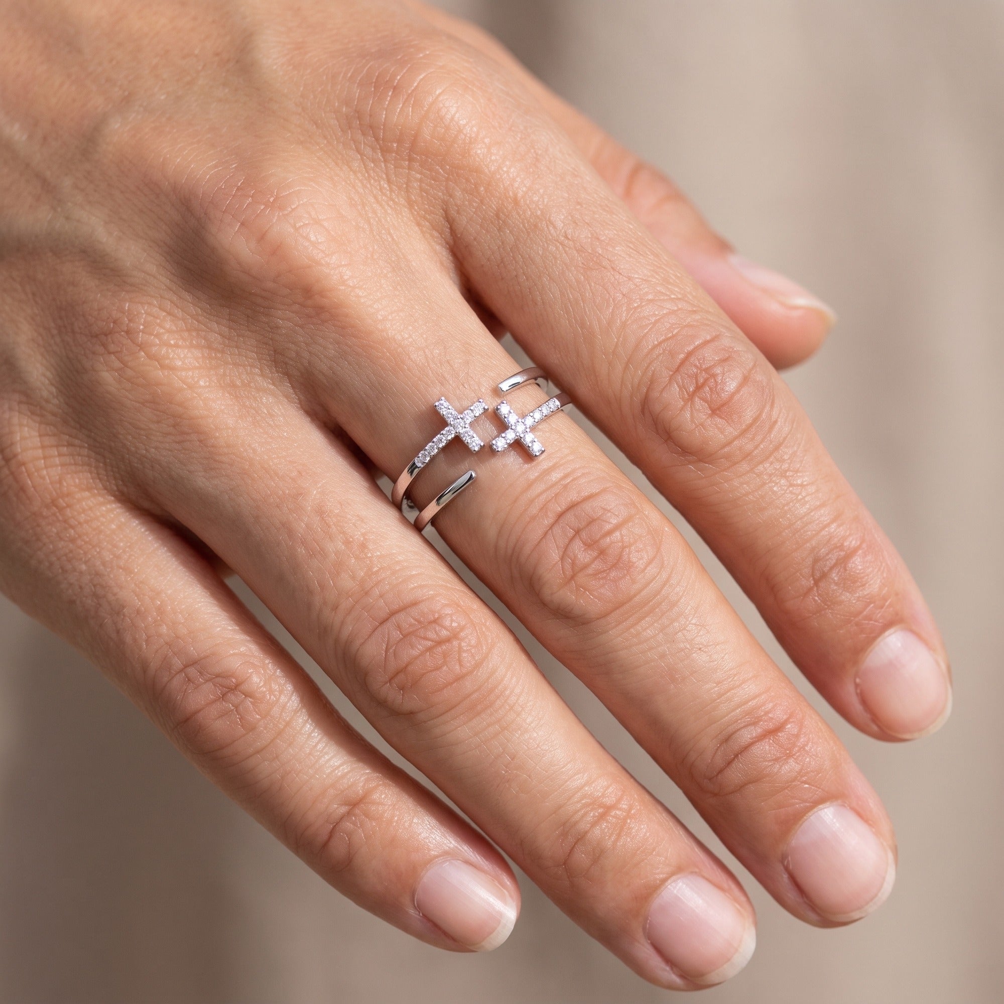 Anillo doble cruz de circonias plateado puesto en la mano