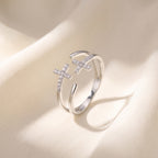 Anillo doble cruz plateado sobre seda marfil