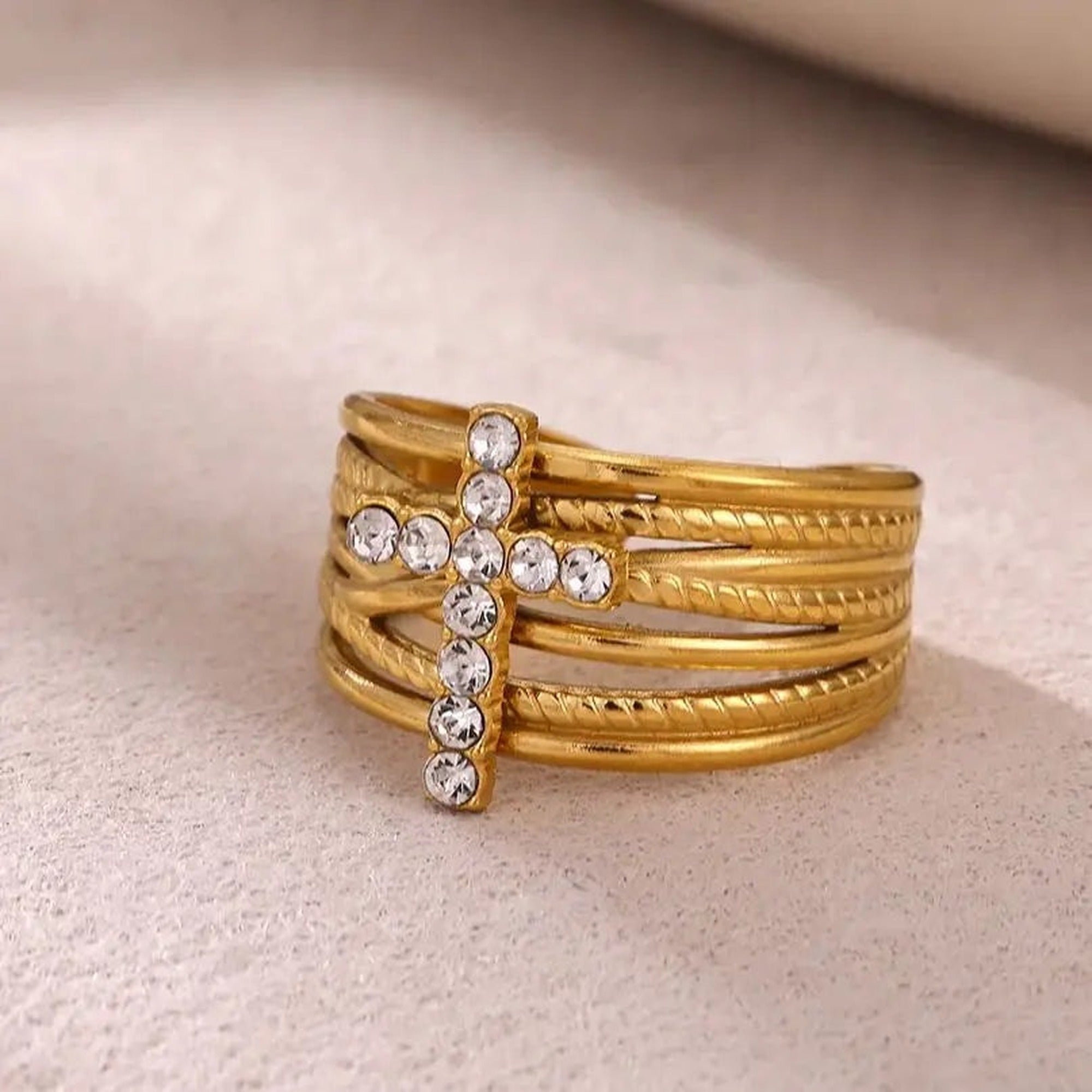 Anillo dorado de aros entrelazados con cruz — vista en ángulo