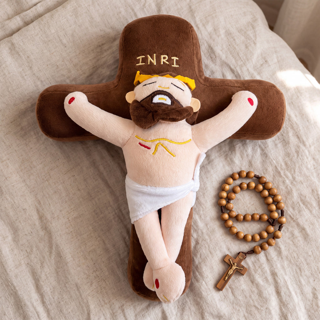 Cojín cruz de Cristo sobre la cama junto a un rosario de madera