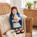 Peluche de la Virgen María con el Niño en una silla de mimbre con manta