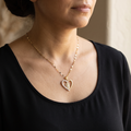 Mujer con el collar de la Virgen de Guadalupe puesto, colgante de corazón dorado sobre blusa negra