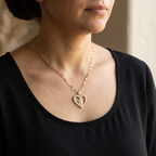 Mujer con el collar de la Virgen de Guadalupe puesto, colgante de corazón dorado sobre blusa negra