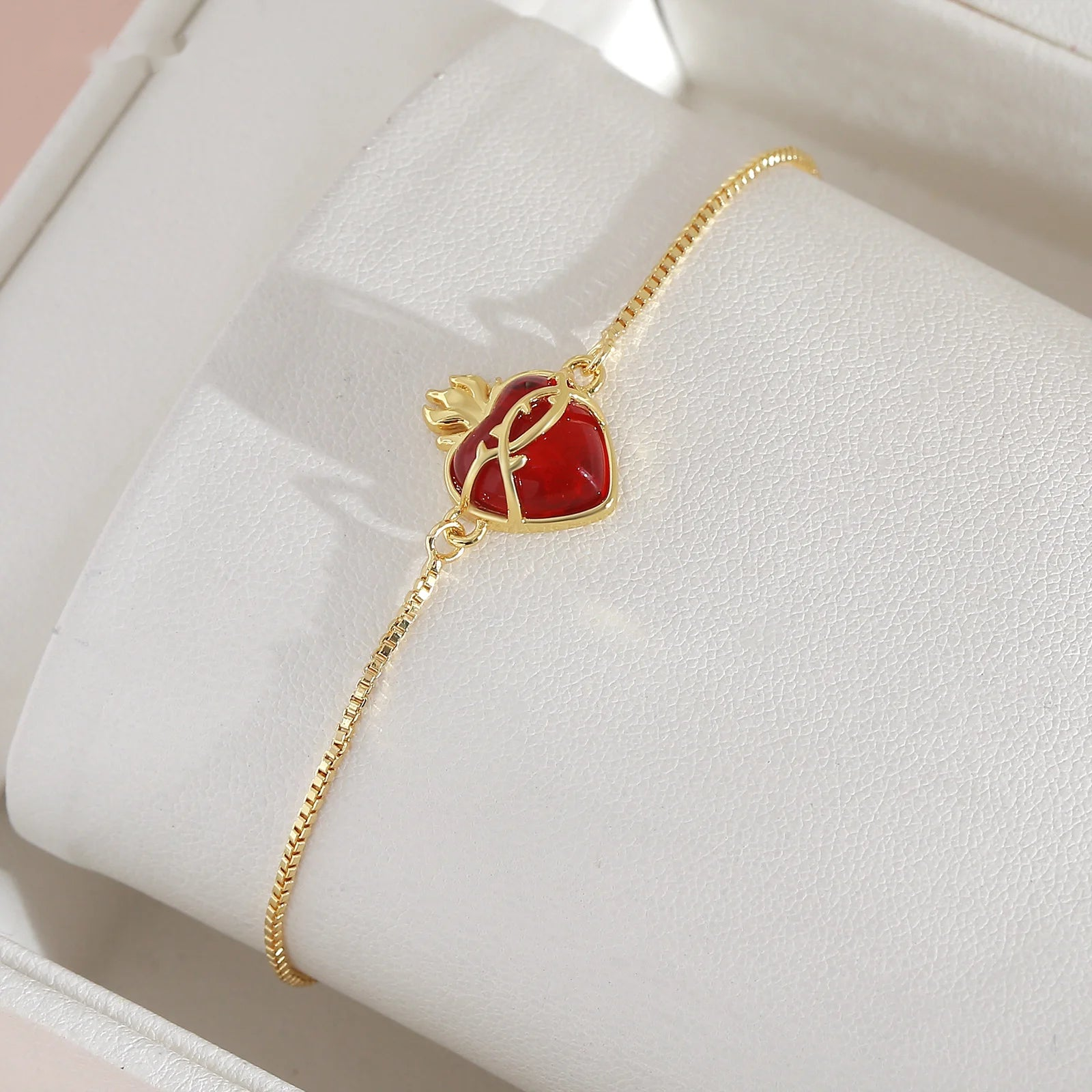 Detalle del Sagrado Corazón de Jesús en cristal rojo y baño dorado, presentado en su estuche de regalo