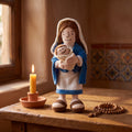 Peluche de la Virgen María junto a una vela encendida y un rosario